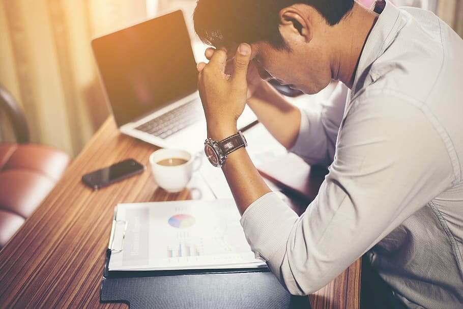 Seorang pria sedang stres ketika bekerja, ia menaruh kepalanya di kedua tangan